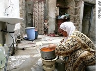 An Iraqi woman cooks on a gas stove in the outdoor yard of her house during an electricity power cut, 27 May 2007