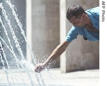 A Romanian gets a splash of water from a fountain in Bucharest, 26 June 2007