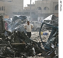 A man stands among destroyed vehicles at a bus station in the Bayaa neighborhood in Baghdad, Iraq,28 June 2007