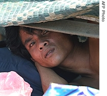 A Cambodian man looks on from a small shelter at a slum-village in down town Phnom Penh, 10 June 2007