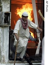 Pakistani students run out of a government office after setting on fire after a clash with police outside the Red Mosque in Islamabad, 03 Jul 2007