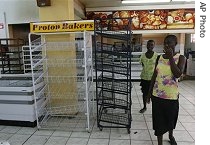 Two women walk past empty bread baskets in a supermarket in Harare, Zimbabwe, 10 Jul 2007