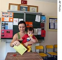 Yeliz Turbay Hizal holds her one-year old son Baris as she votes at a polling station in a primary school in Ankara, 22 Jul 2007
