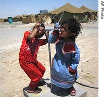 Iraqi children drink water from taps at a refugee camp for internally displaced people outside Najaf, 16 Jun 2007