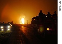 Smoke and flames from an explosion at a gas pipeline are seen in the background as a Mexican army truck drives by near Queretaro, Mexico, 10 July 2007
