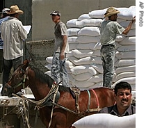 Palestinians carry flour outside a United Nations food aid distribution center in the Jebaliya Refugee Camp, northern Gaza Strip, 18 July 2007