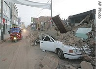 Mototaxi drives past a car covered with rubble in area hit by earthquake late Wednesday in Ica, some 275 km. southeast of Lima, 16 Aug 2007