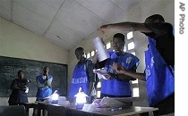 Poll workers count presidential ballots with the help of battery-powered lights at a polling station in Freetown, 11 Aug 2007
