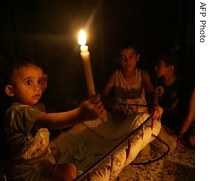 A Palestinian toddler holds up a lit candle in his house after the electricity was cut off in his area of Gaza City, 17 Aug. 2007