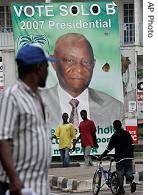 Pedestrians pass in front of a campaign banner for presidential candidate and current vice president Solomon Berewa following the close of the polls, in Freetown 