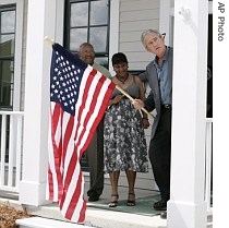 President Bush, right, helps the White family hang a flag outside their new home during a visit New Orleans, 29 Aug 2007
