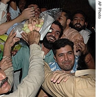 Supporters of Pakistan's ousted former prime minister Nawaz Sharif share sweets to celebrate their leader's decision to come back to his country 30 Aug 2007
