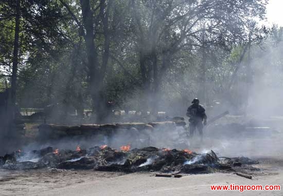Smoke billows from burning tires around a Ukrainian special forces soldier at a checkpoint following an attack by Ukrainian troops outside Slovyansk, Ukraine, Thursday, April 24, 2014.