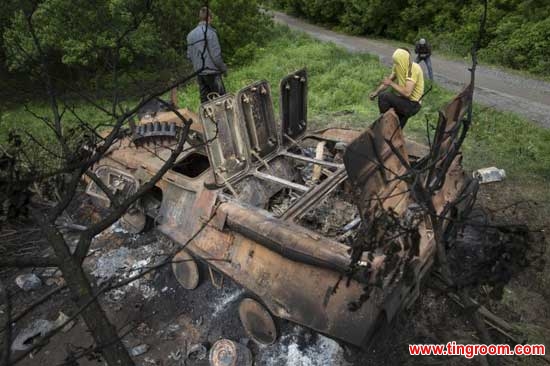 Local citizens collect parts of a seized APC that was set alight during a fighting between and government troops at Oktyabrskoye village, about 20 km. (12 miles) from Kramatorsk, eastern Ukraine, Wednesday, May 14, 2014. 