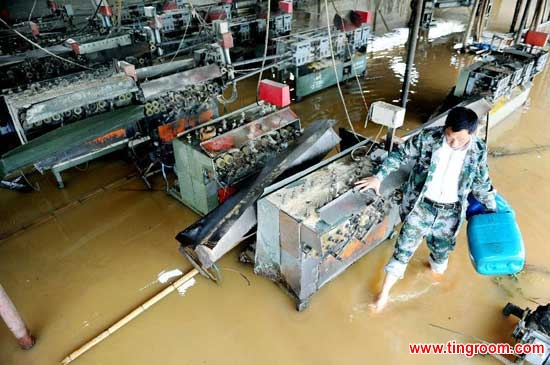A man transports materials in his flooded bamboo ware factory in Dexing City, east China