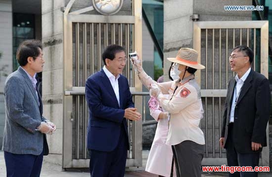A staff worker checks the temperature of Seoul Mayor Park Won-soon (2nd L) at an elementary school in Seoul, South Korea, on June 17, 2015. South Korea on Wednesday reported eight more cases of the Middle East Respiratory Syndrome (MERS) infection and one more death, bringing the death toll to 20. (Xinhua)