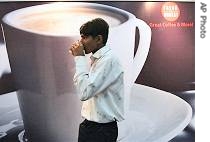 A visitor sips coffee next to a poster advertising a coffee brand at the India International Coffee Festival 2007 in Bangalore (File photo - 24 Feb 2007)